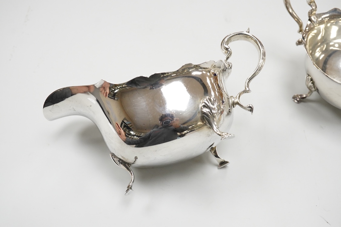 A pair of George V silver sauceboats, with scroll handles, on three hoof feet, E S Barnsley & Co, Birmingham, 1921, length approx. 17.3cm, 10.2oz.